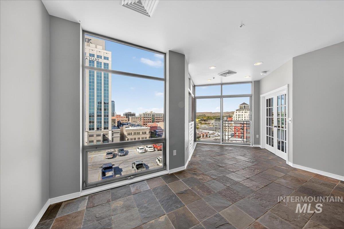Empty room with expansive windows, a city view, stone tile floors, and recessed lighting