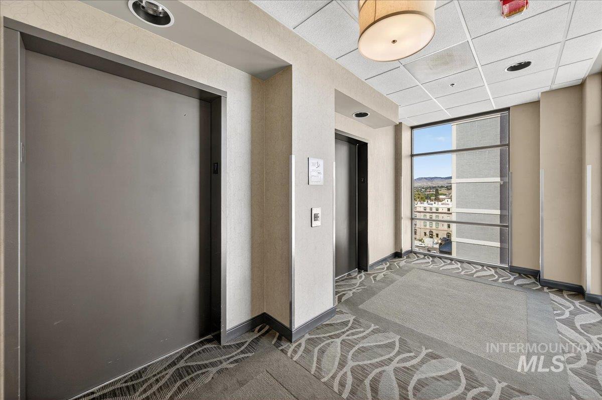 Hall with elevator, carpet floors, a paneled ceiling, and a mountain view