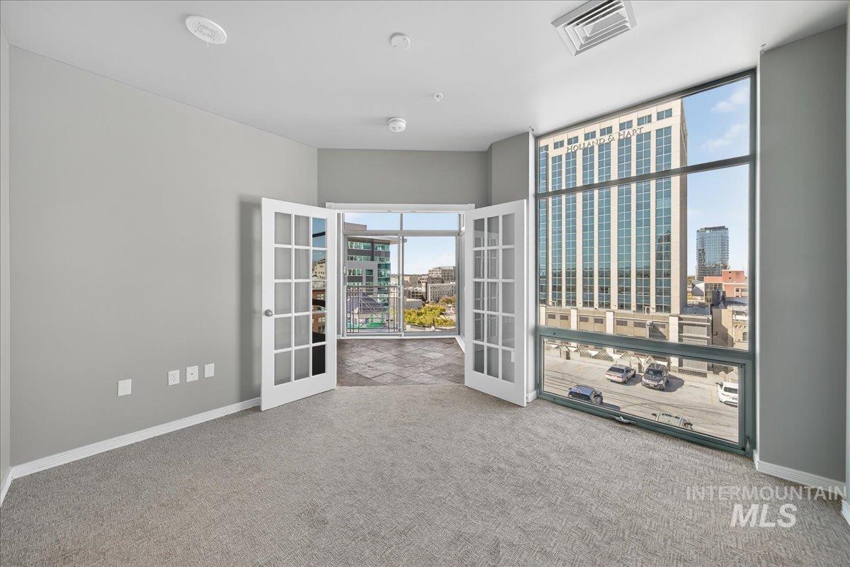 Empty room with light carpet, french doors, and a city view