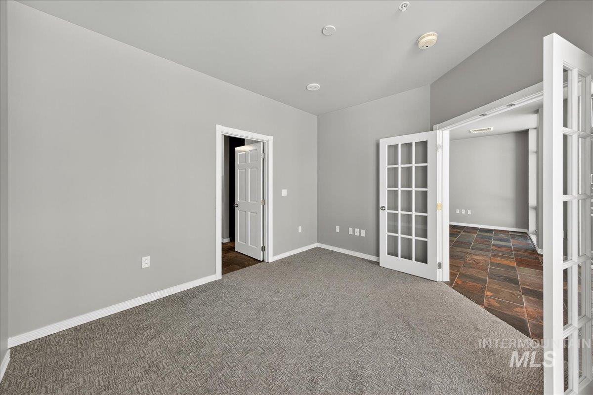 Unfurnished room featuring dark colored carpet and french doors