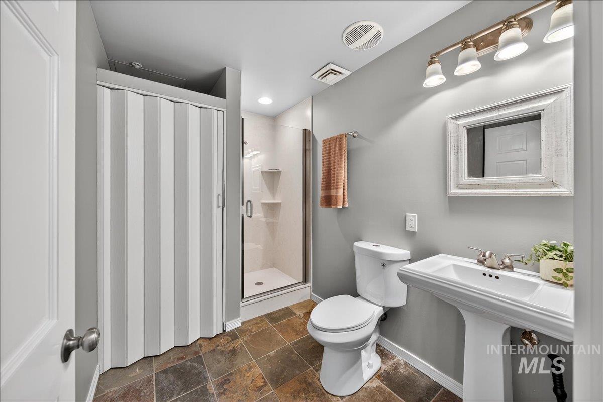 Bathroom featuring a stall shower and dark stone finish floors