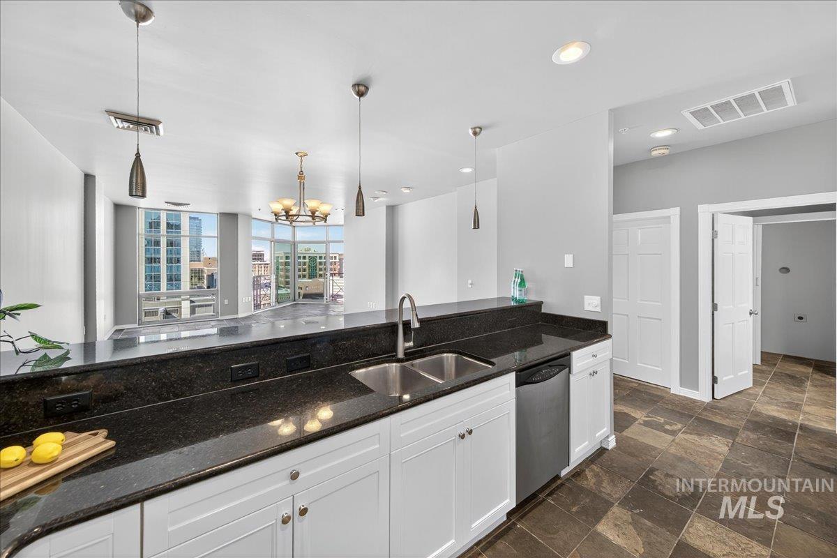 Kitchen with dark stone counters, decorative light fixtures, dark stone finish flooring, white cabinets, and recessed lighting