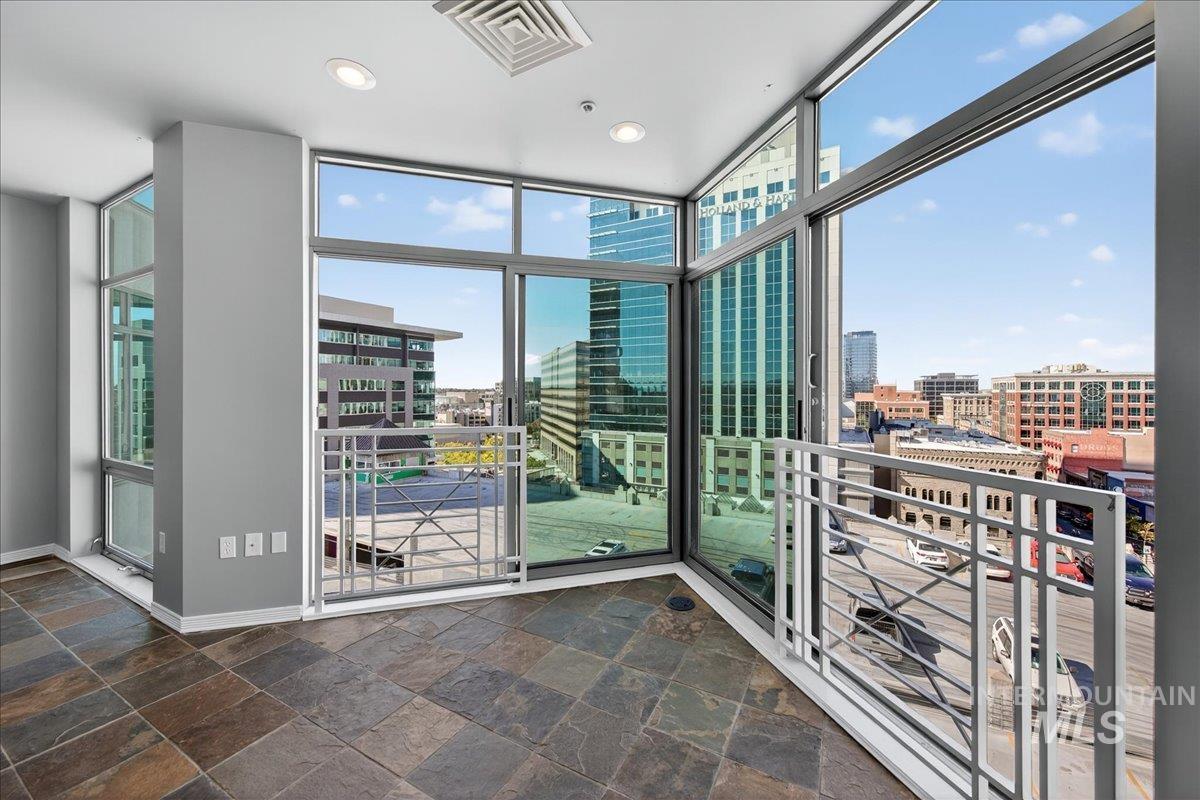 Interior space with a wall of windows, a city view, recessed lighting, and stone tile flooring