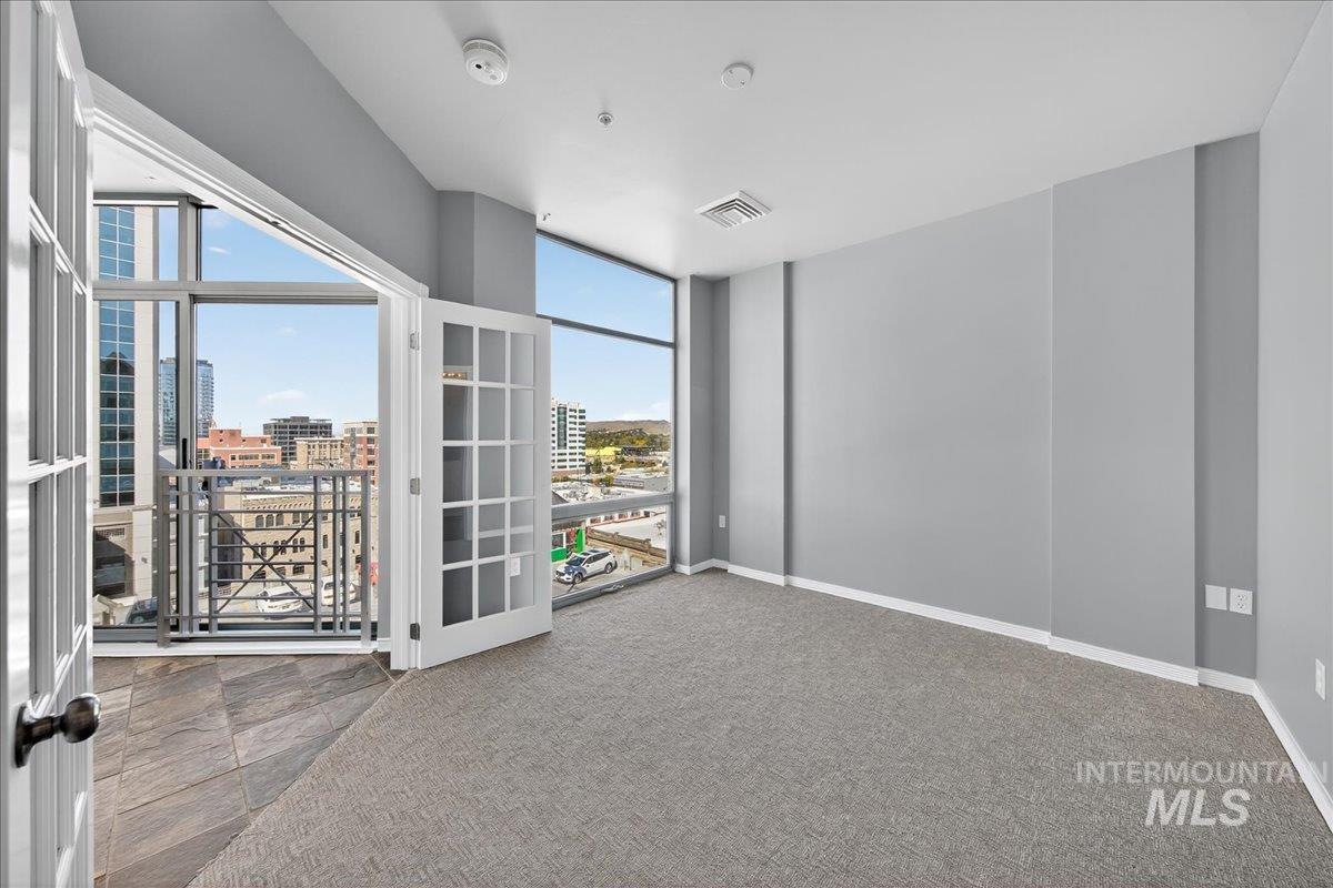 Carpeted spare room featuring a city view and baseboards