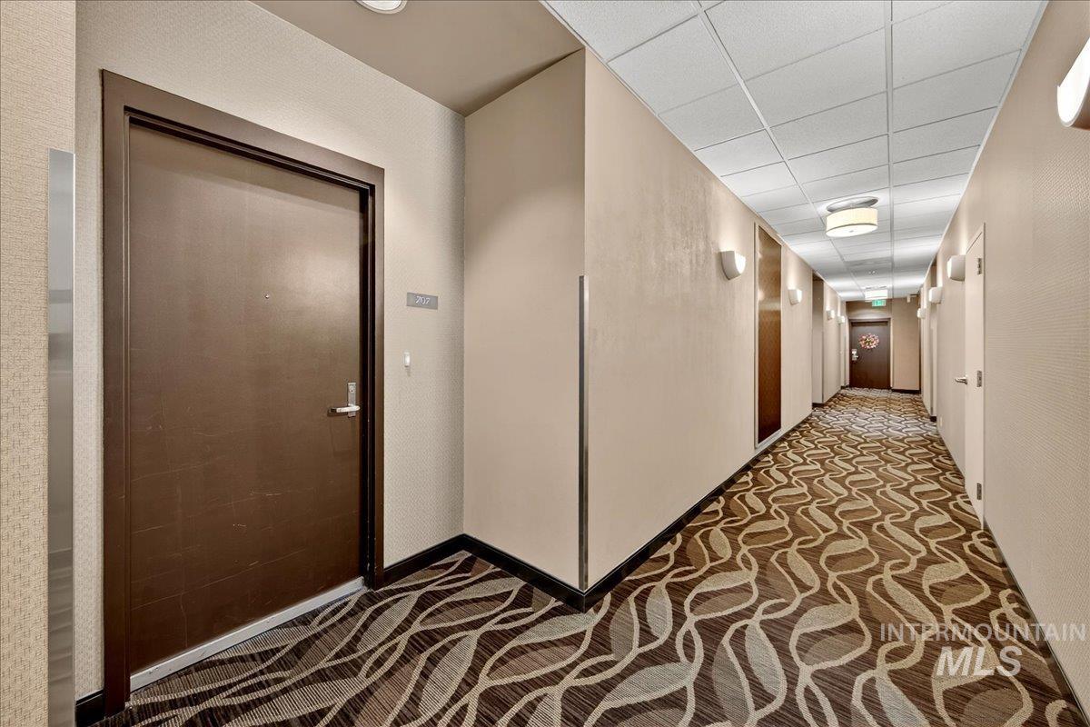 Hall with a paneled ceiling and baseboards