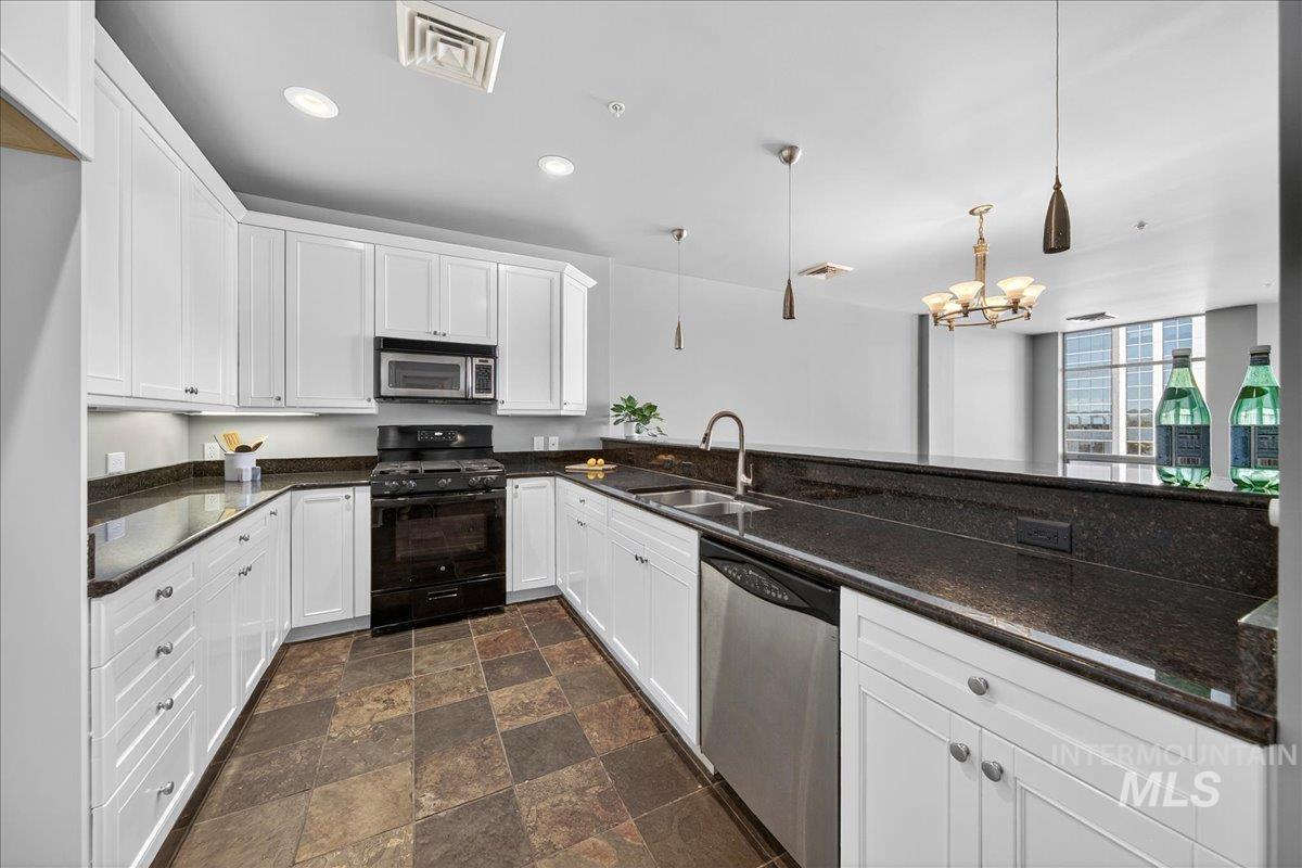 Kitchen featuring appliances with stainless steel finishes, pendant lighting, dark stone counters, white cabinetry, and recessed lighting
