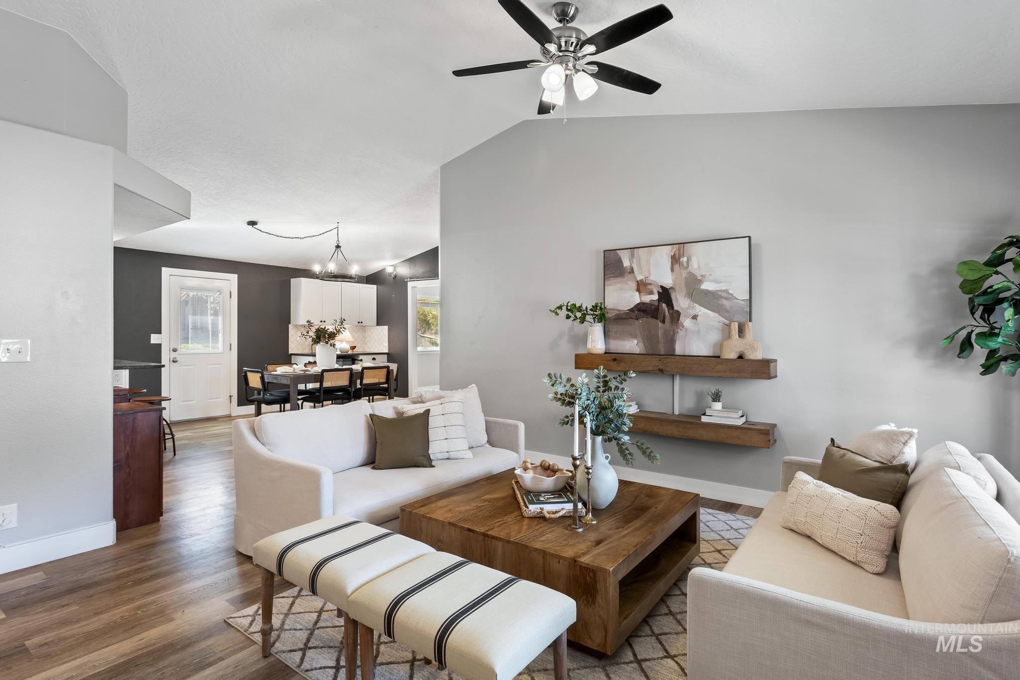 Living room with vaulted ceiling, wood finished floors, and a ceiling fan