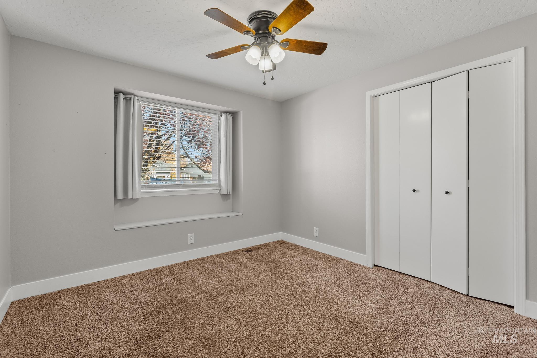 Unfurnished bedroom featuring carpet, a closet, ceiling fan, and a textured ceiling