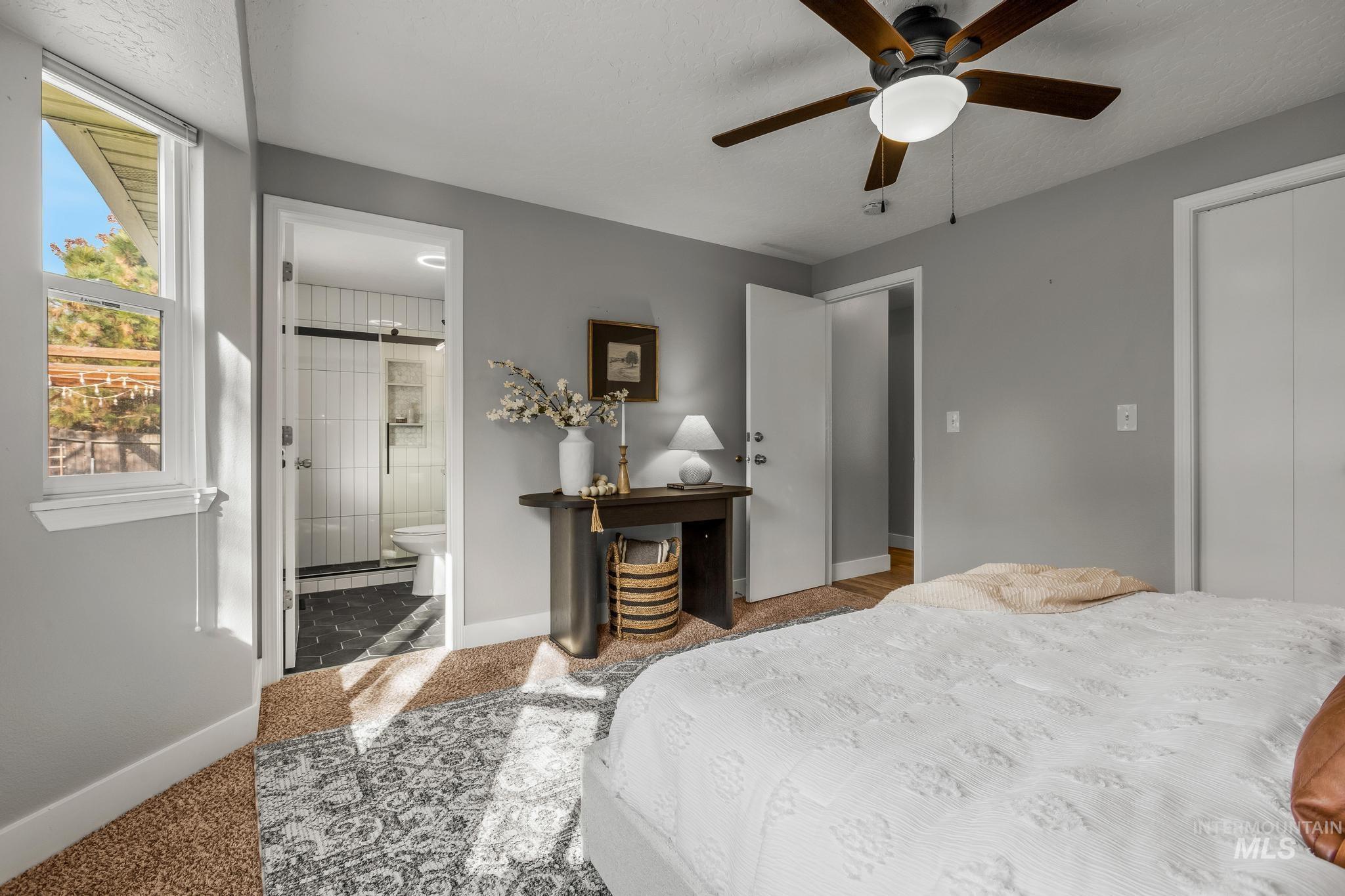 Bedroom with carpet, ceiling fan, connected bathroom, a barn door, and baseboard heating