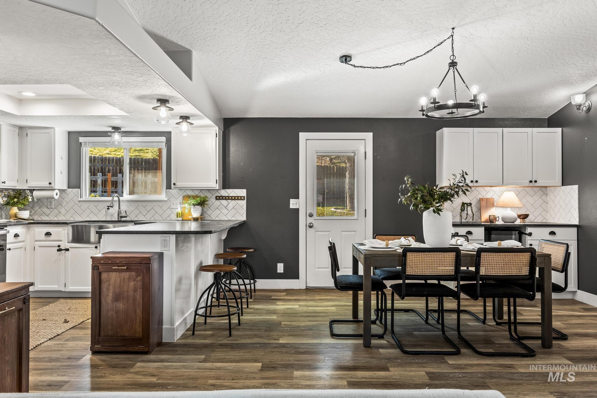 Kitchen featuring decorative backsplash, white cabinets, a breakfast bar, and a textured ceiling