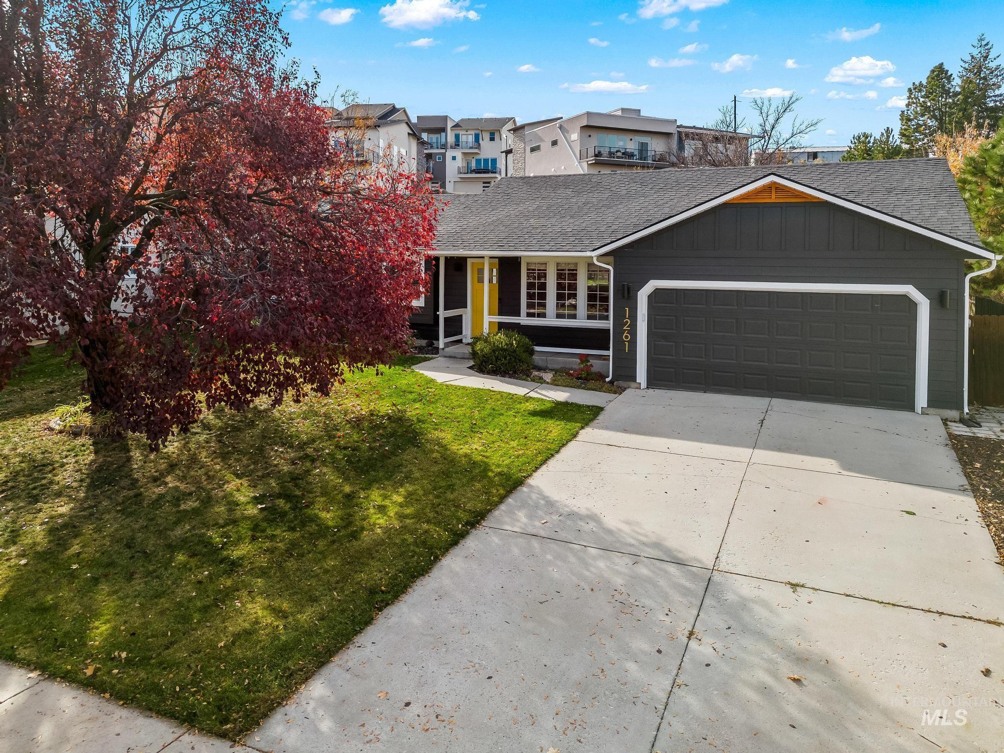 View of front of house with concrete driveway, roof with shingles, an attached garage, and a front lawn