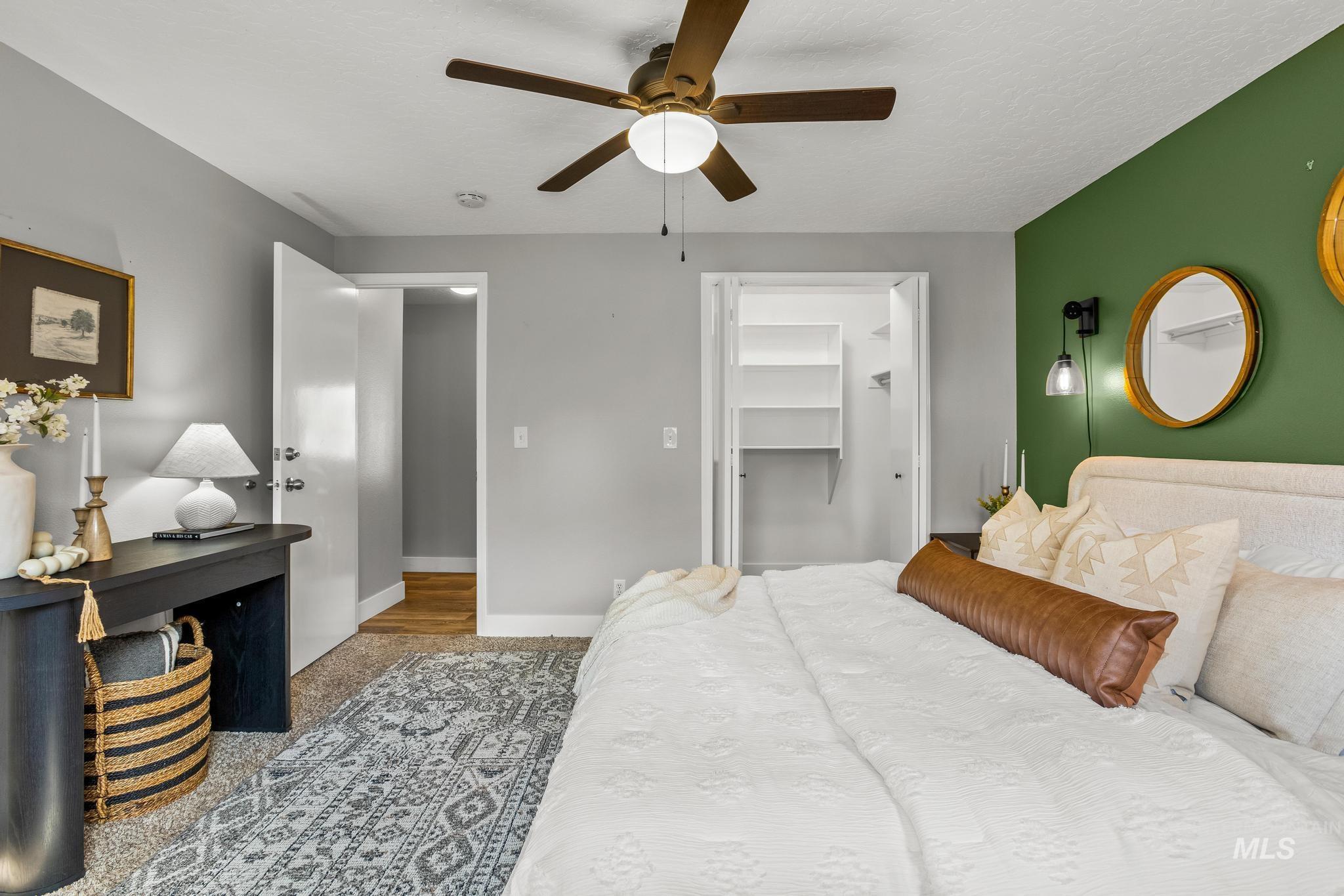 Bedroom with a walk in closet, a ceiling fan, carpet floors, and a textured ceiling