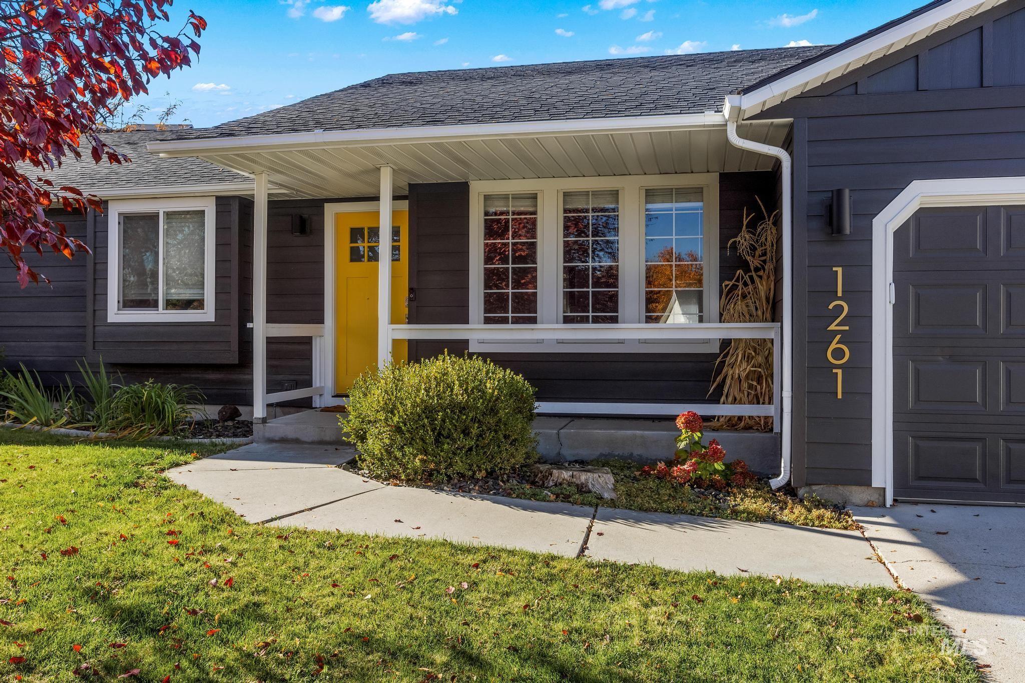 View of exterior entry with a shingled roof, covered porch, a garage, and a yard
