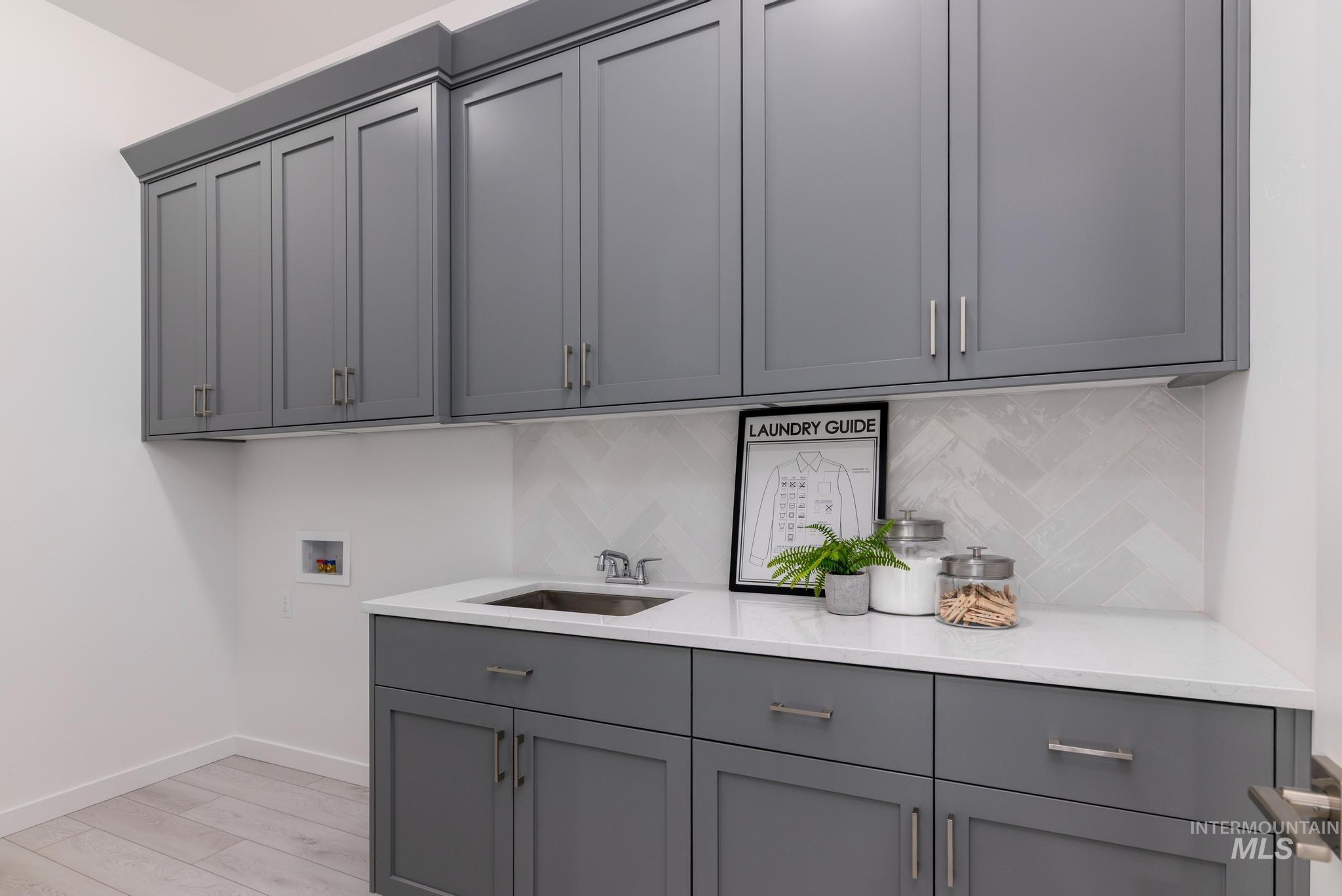 Laundry room with light wood-style flooring, cabinet space, and washer hookup