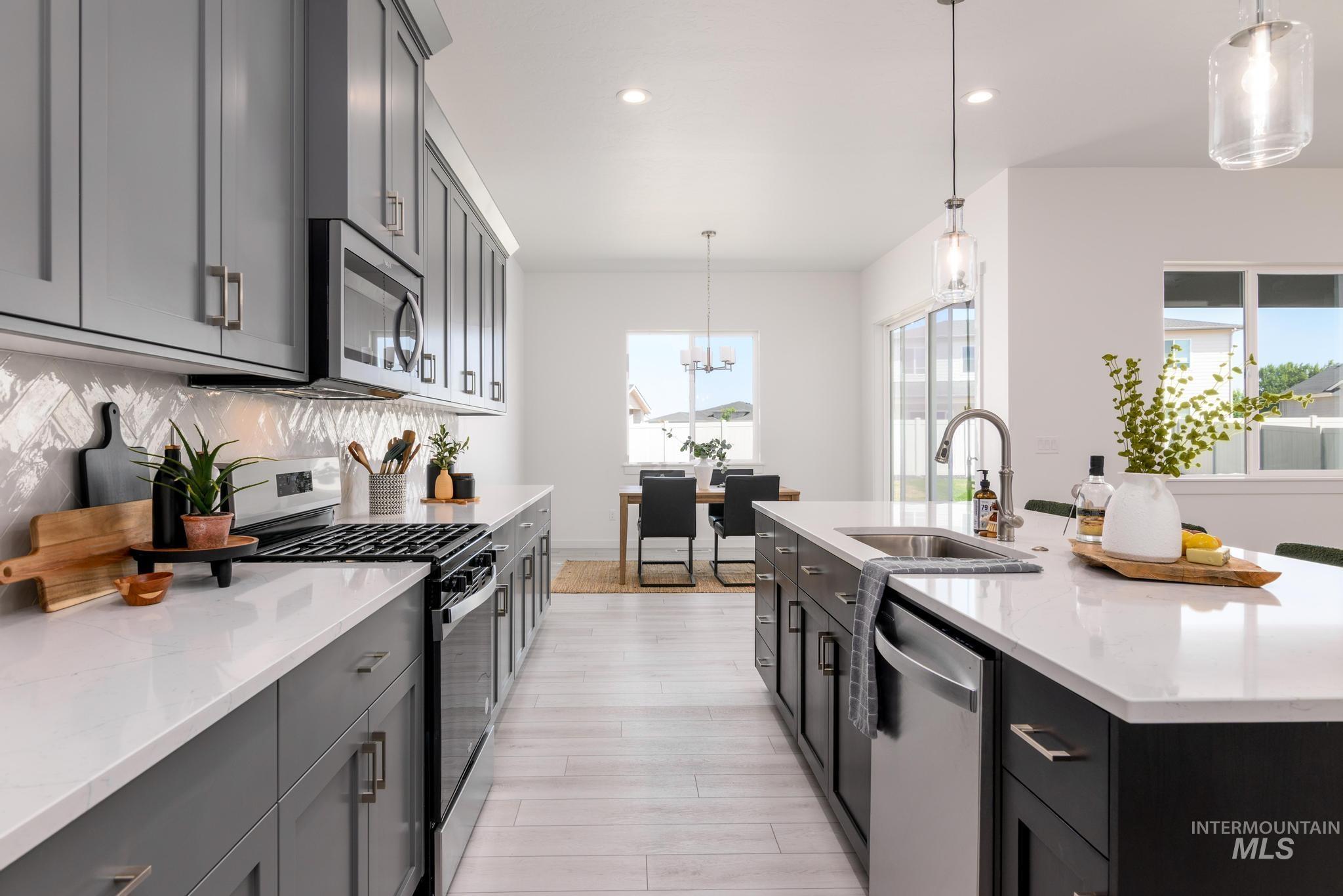 Kitchen featuring appliances with stainless steel finishes, decorative light fixtures, light stone countertops, recessed lighting, and tasteful backsplash