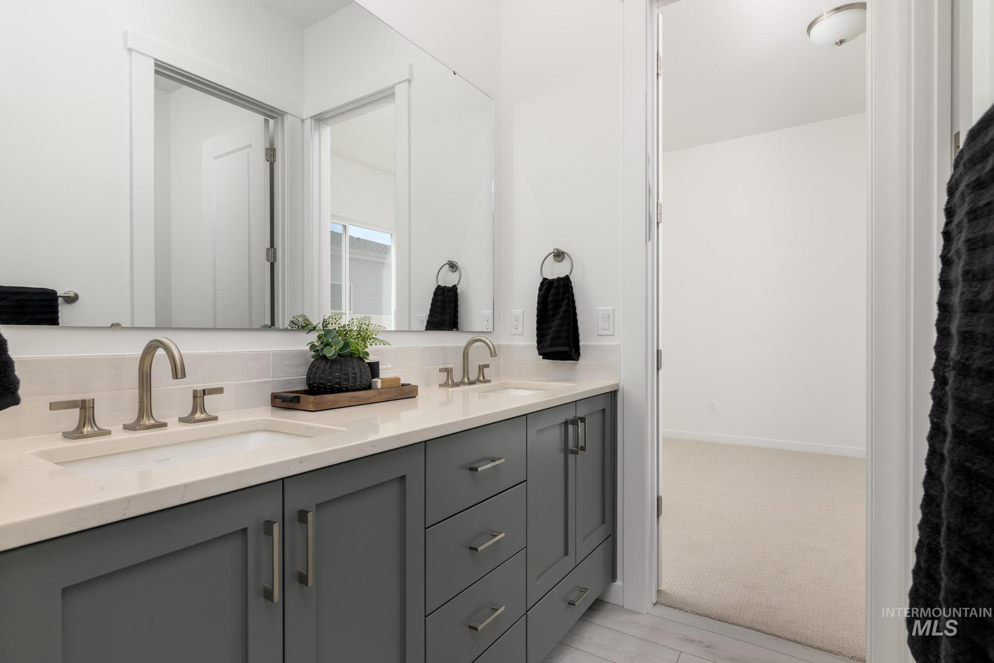 Full bath with double vanity and light carpet