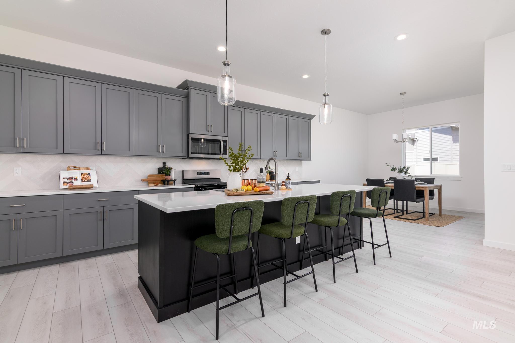 Kitchen with backsplash, pendant lighting, a kitchen island with sink, a breakfast bar, and recessed lighting