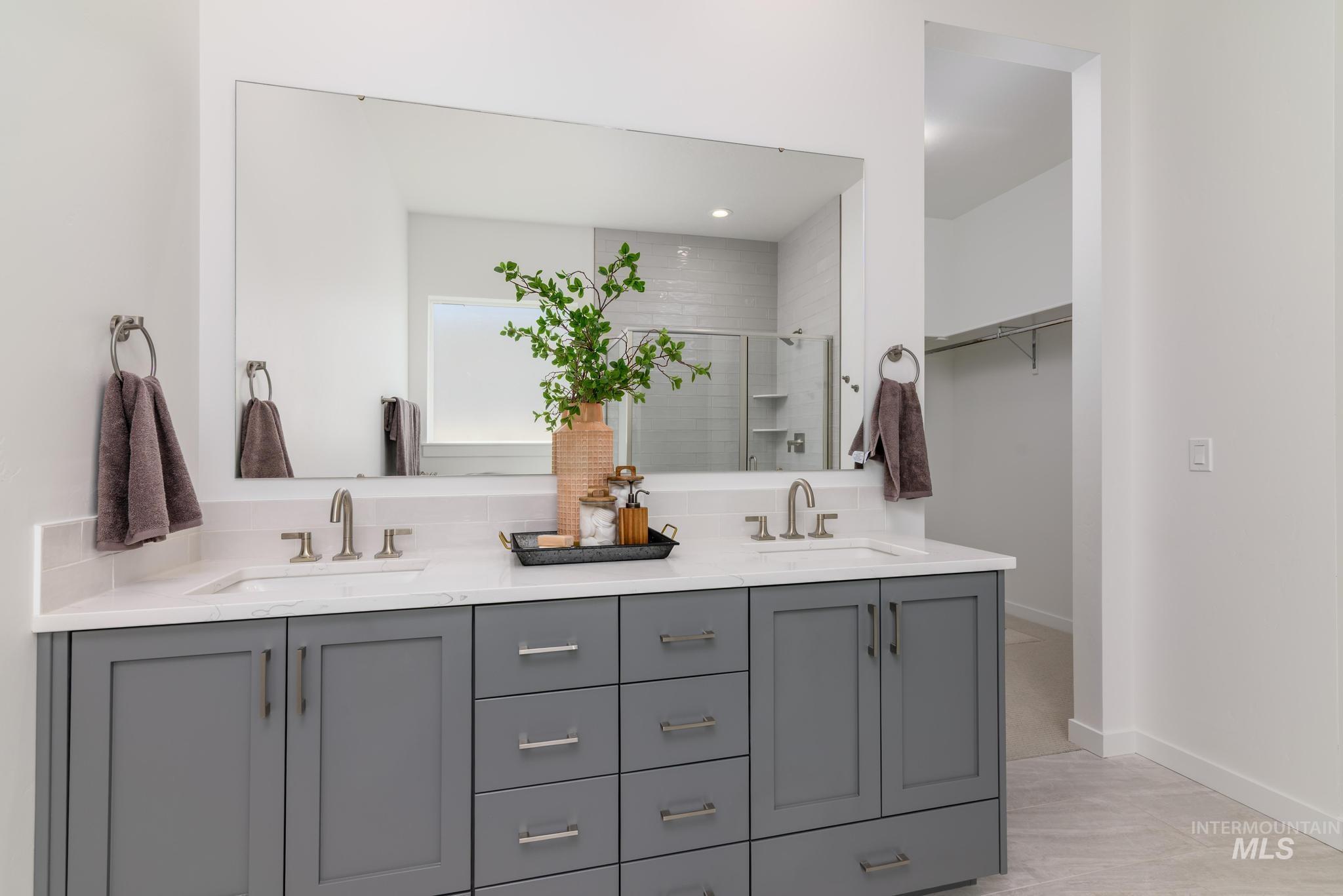 Bathroom featuring a stall shower, double vanity, and a spacious closet