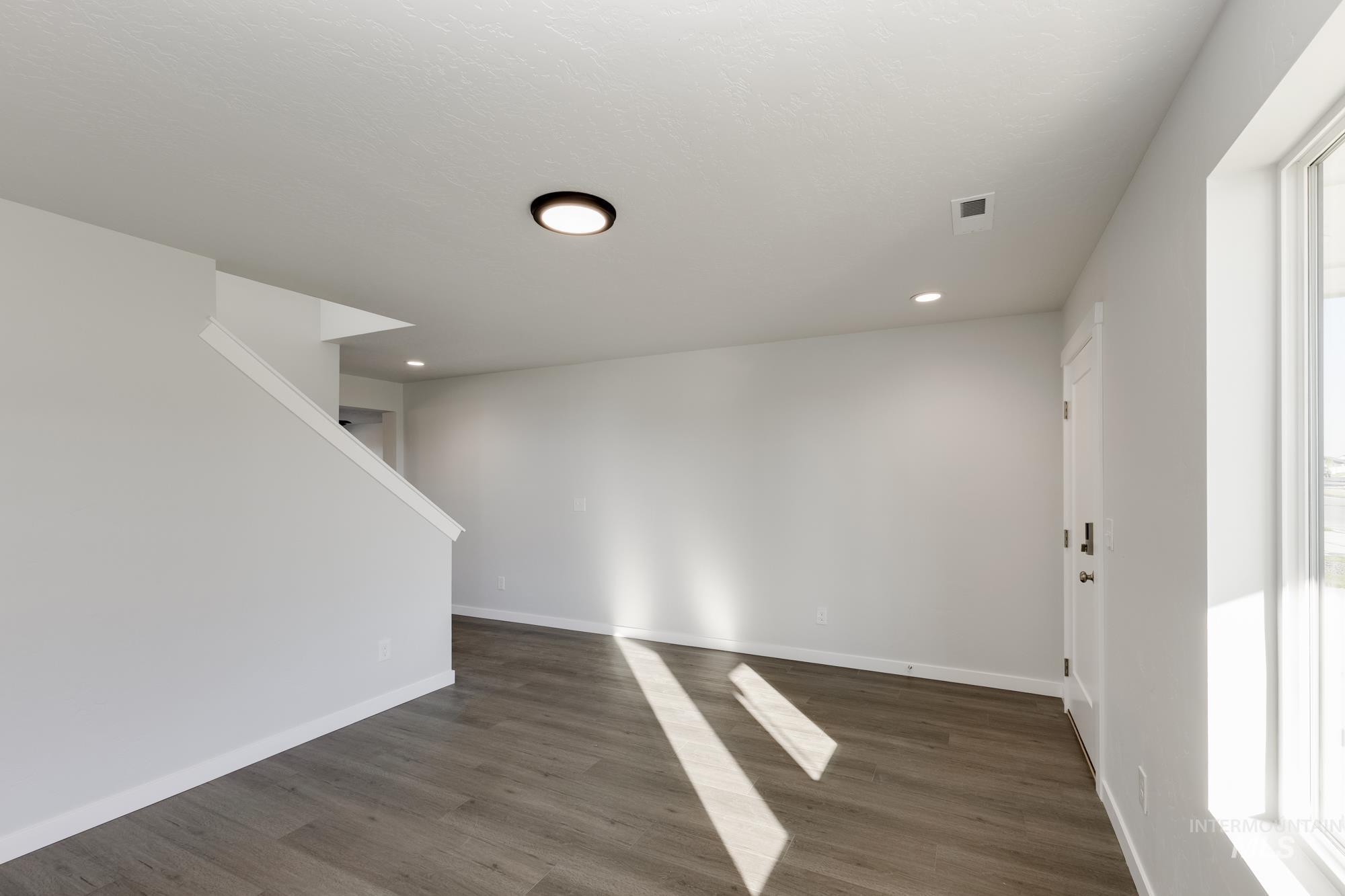 Spare room featuring dark wood-style flooring, plenty of natural light, and recessed lighting