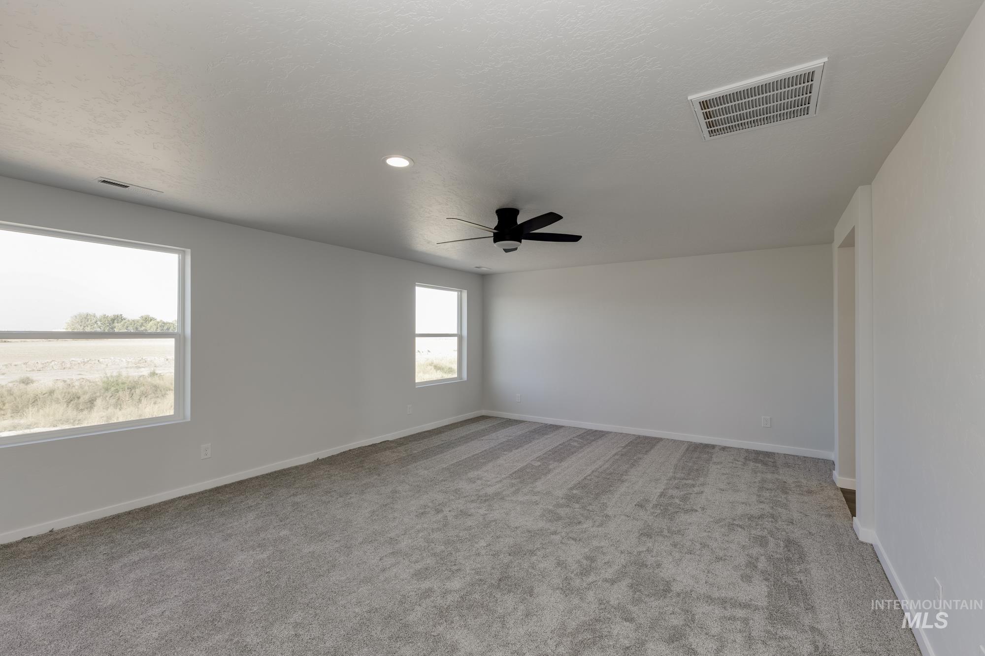 Empty room with light colored carpet, a ceiling fan, a textured ceiling, and recessed lighting