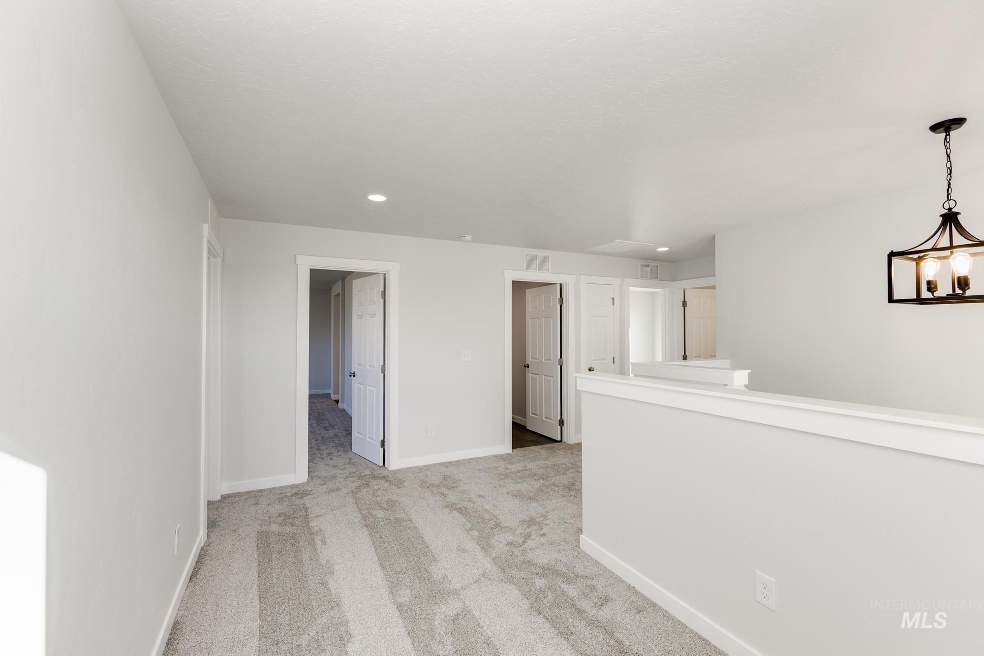 Unfurnished room with light colored carpet, recessed lighting, and a chandelier
