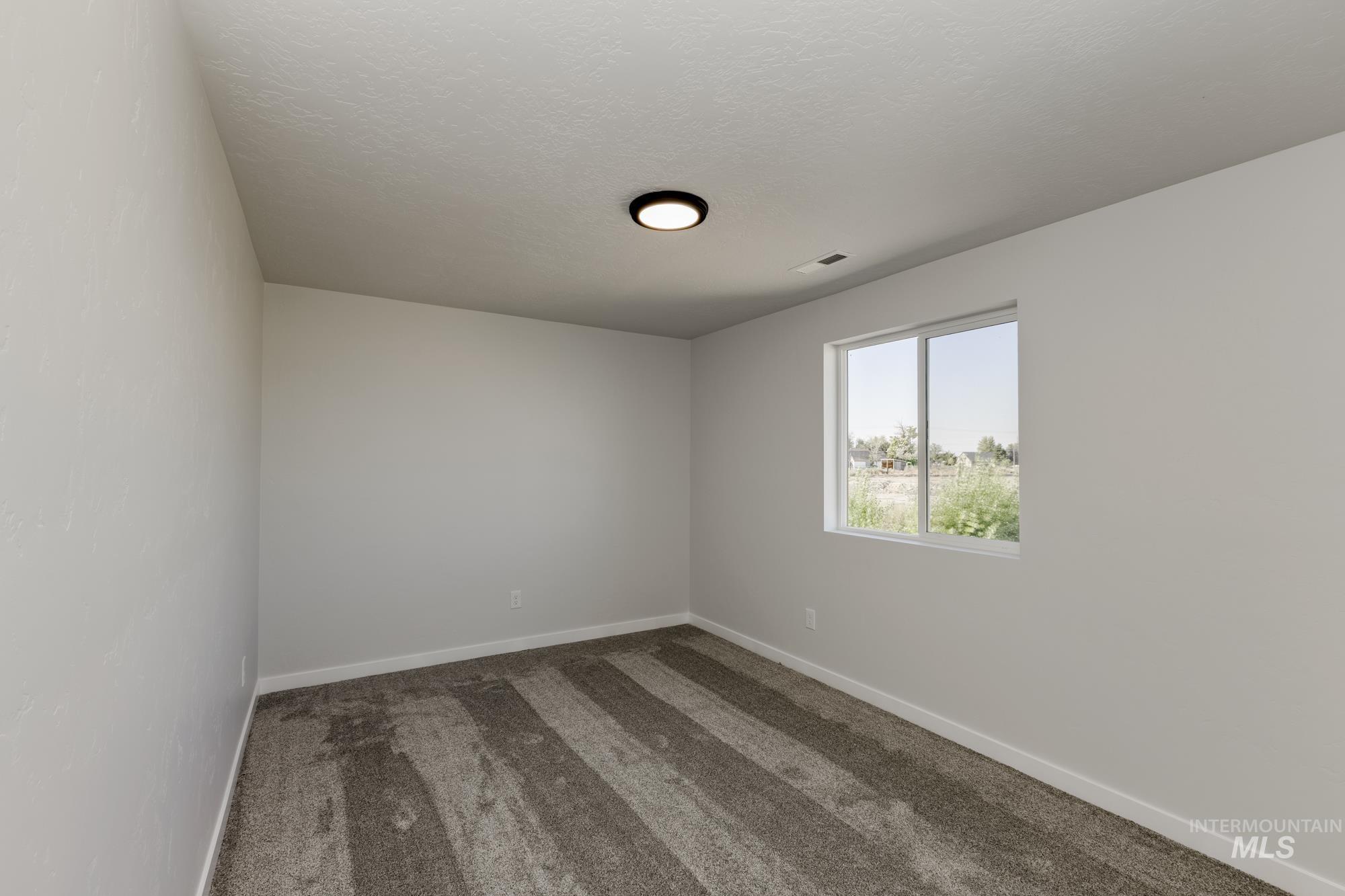Carpeted spare room with baseboards and a textured ceiling