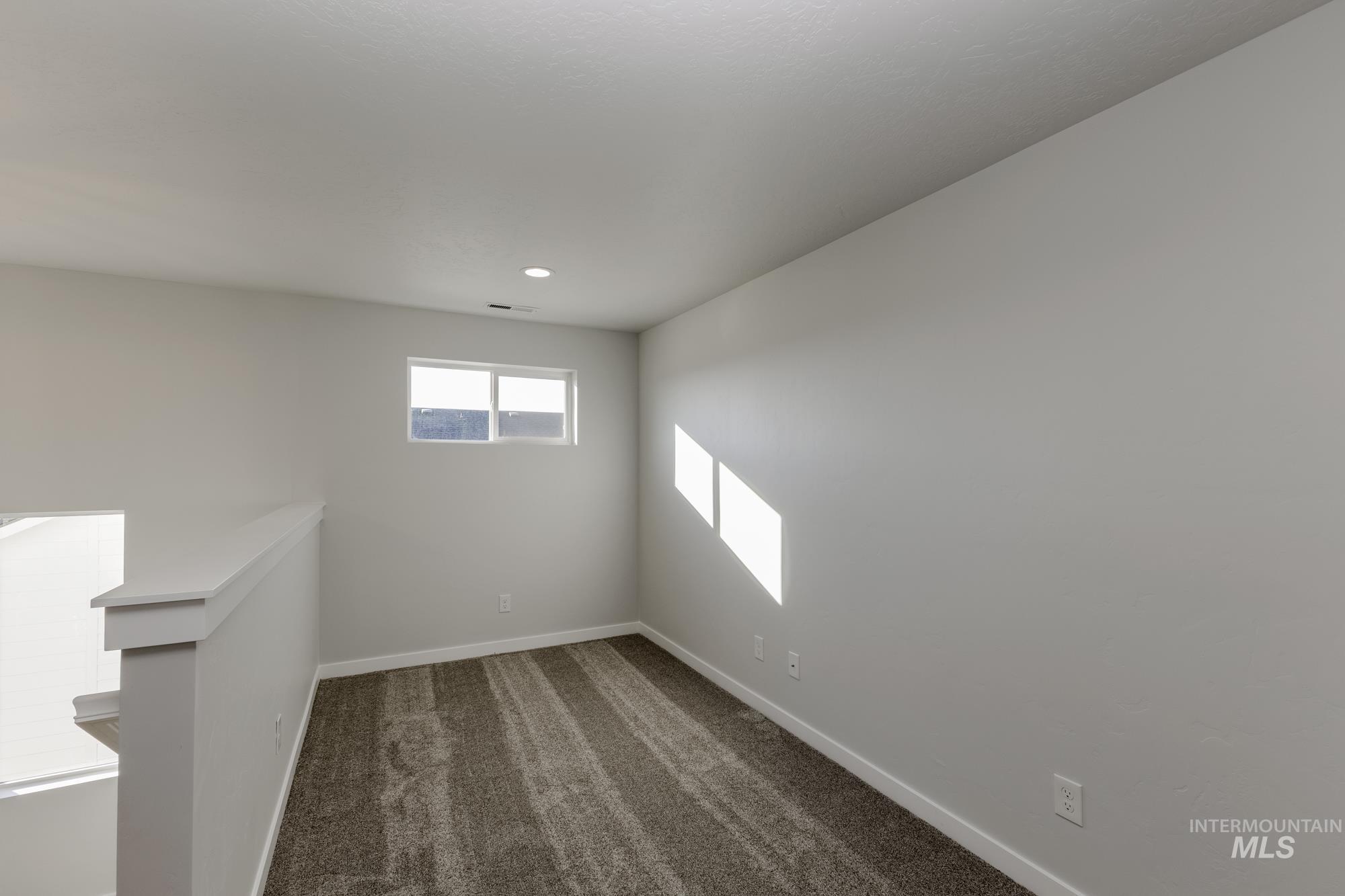 Empty room featuring dark colored carpet and baseboards