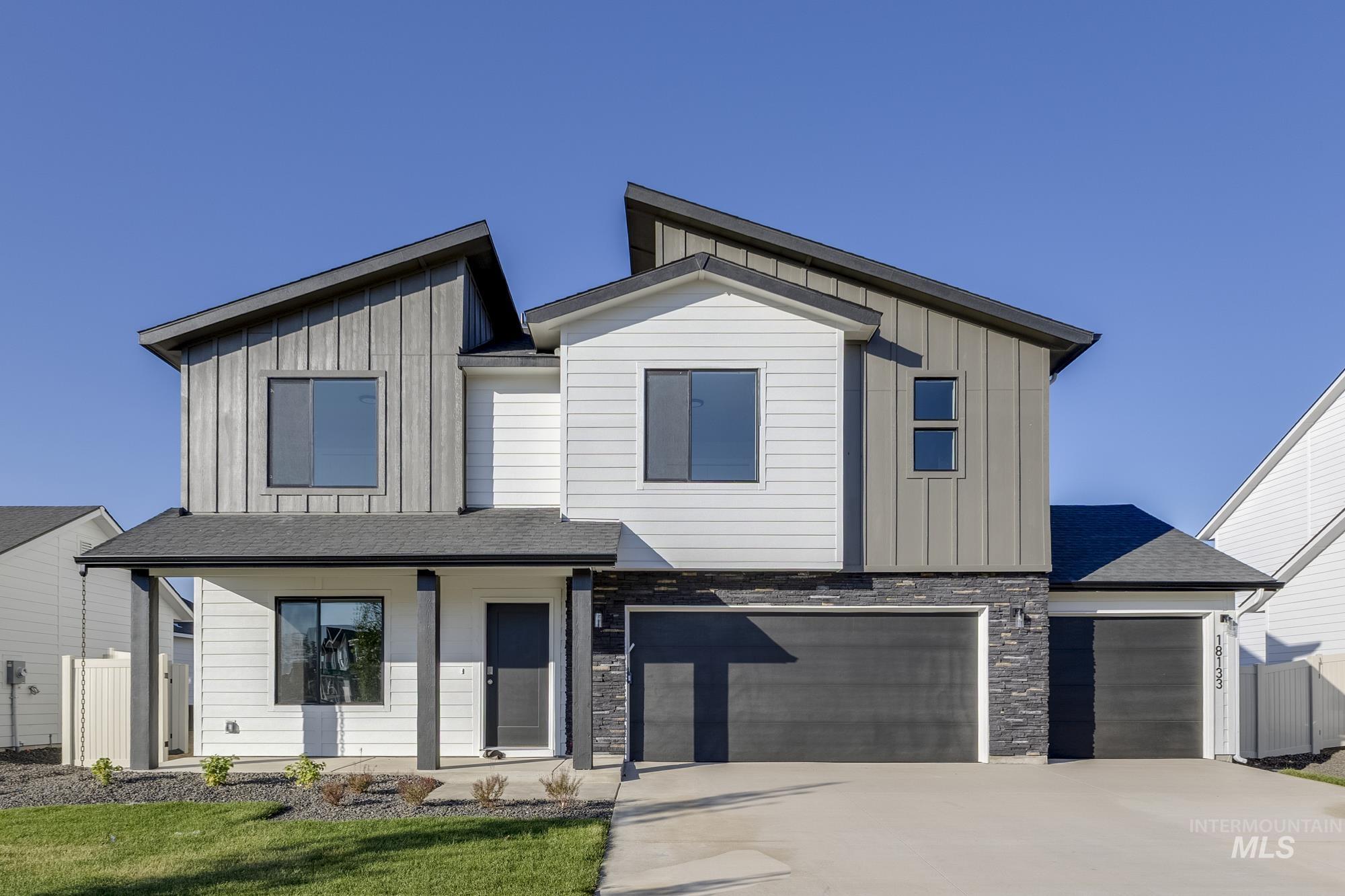 Contemporary house featuring board and batten siding, covered porch, driveway, and stone siding