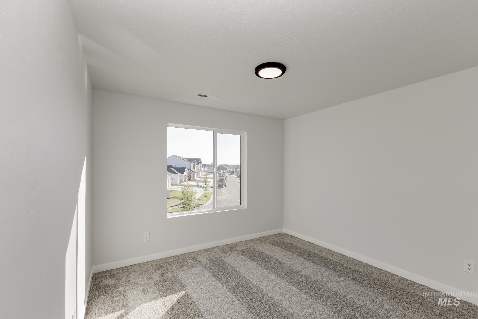 Spare room featuring light carpet and baseboards