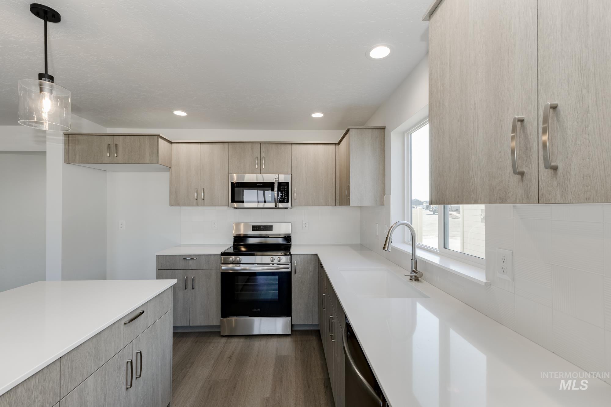 Kitchen with stainless steel appliances, dark wood-style floors, decorative light fixtures, modern cabinets, and recessed lighting