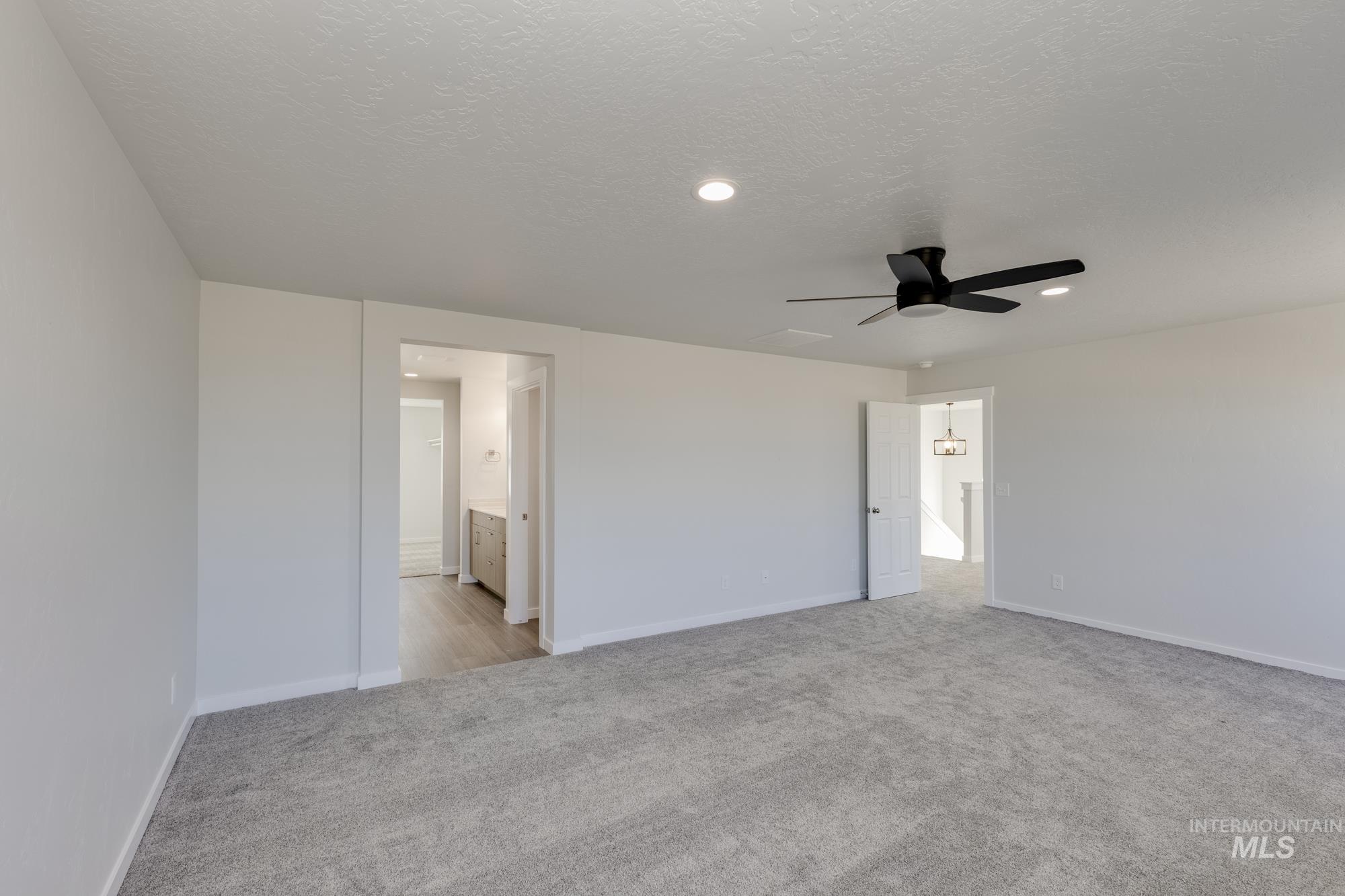 Unfurnished bedroom featuring light carpet, a ceiling fan, a textured ceiling, ensuite bath, and recessed lighting