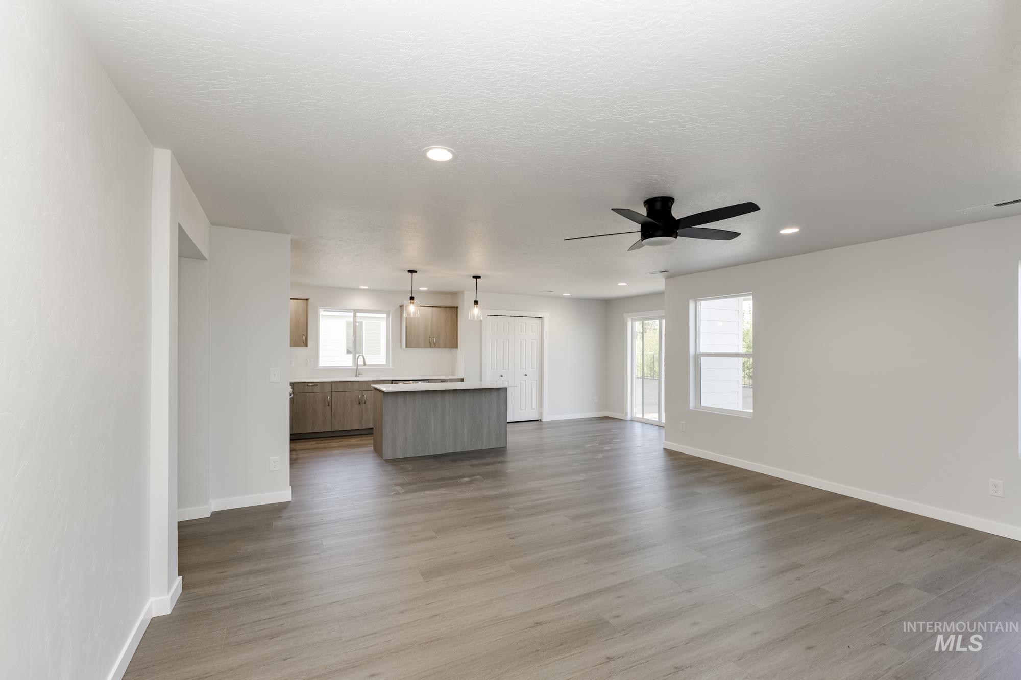 Unfurnished living room featuring light wood finished floors, a textured ceiling, a ceiling fan, and recessed lighting