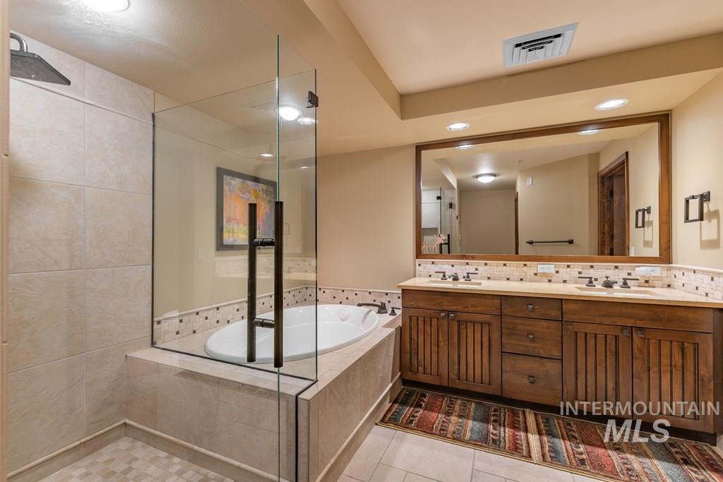 Bathroom featuring double vanity, a bath, recessed lighting, tasteful backsplash, and light tile patterned flooring