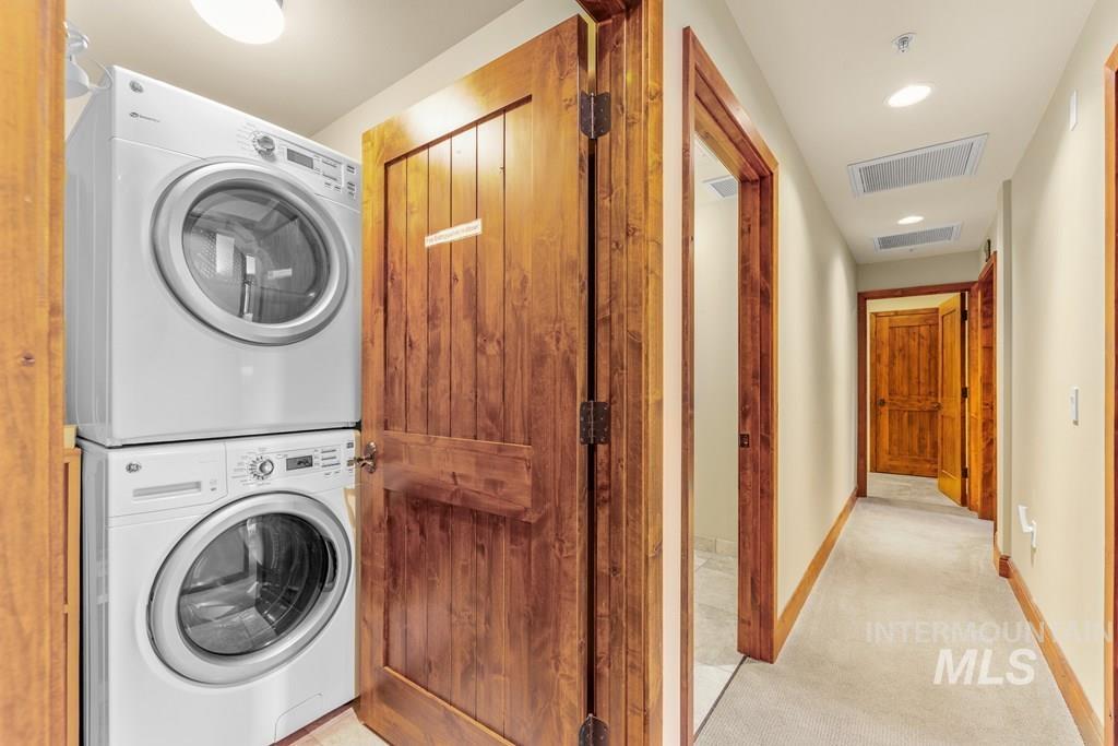Washroom featuring estacked washer and dryer, recessed lighting, and light colored carpet
