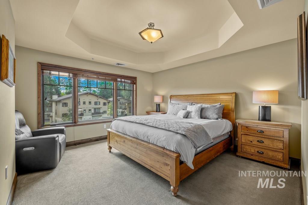 Bedroom with a raised ceiling and carpetwith a walk-in closet and an ensuite bath.