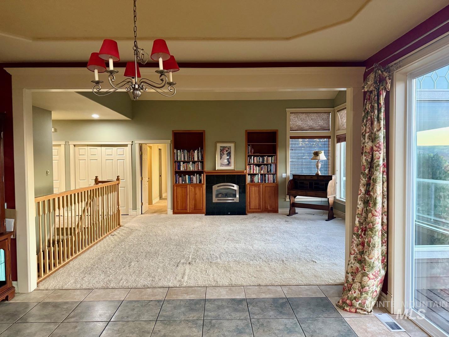Carpeted entrance foyer with a chandelier, a fireplace, and tile patterned flooring