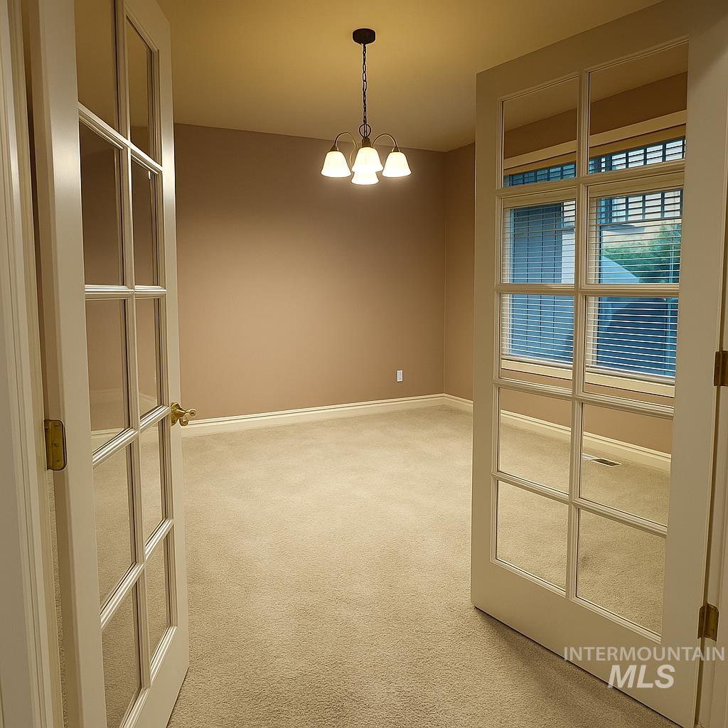Empty room featuring light carpet and hanging lights