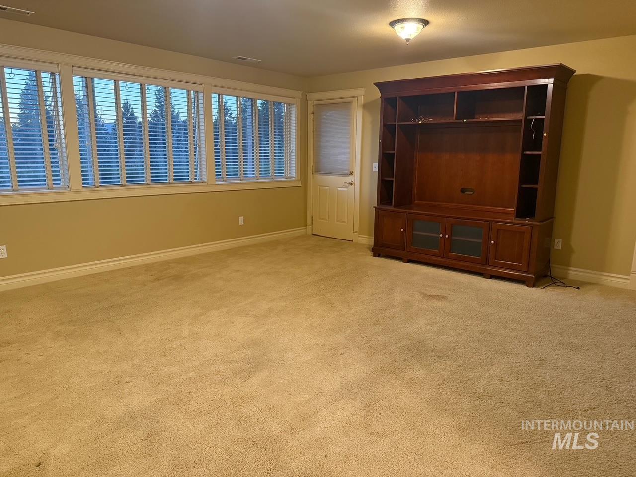 Unfurnished living room featuring light colored carpet and baseboards