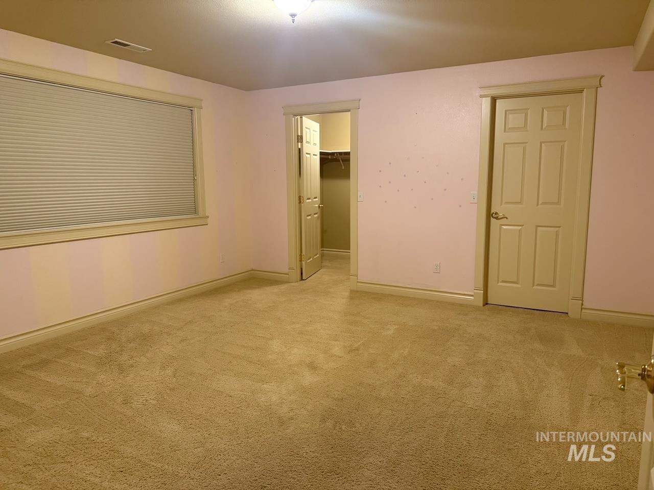 Unfurnished bedroom with a walk in closet and light colored carpet