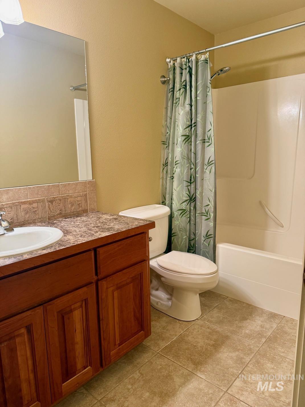 Bathroom with shower / tub combo, vanity, light tile patterned floors, and decorative backsplash
