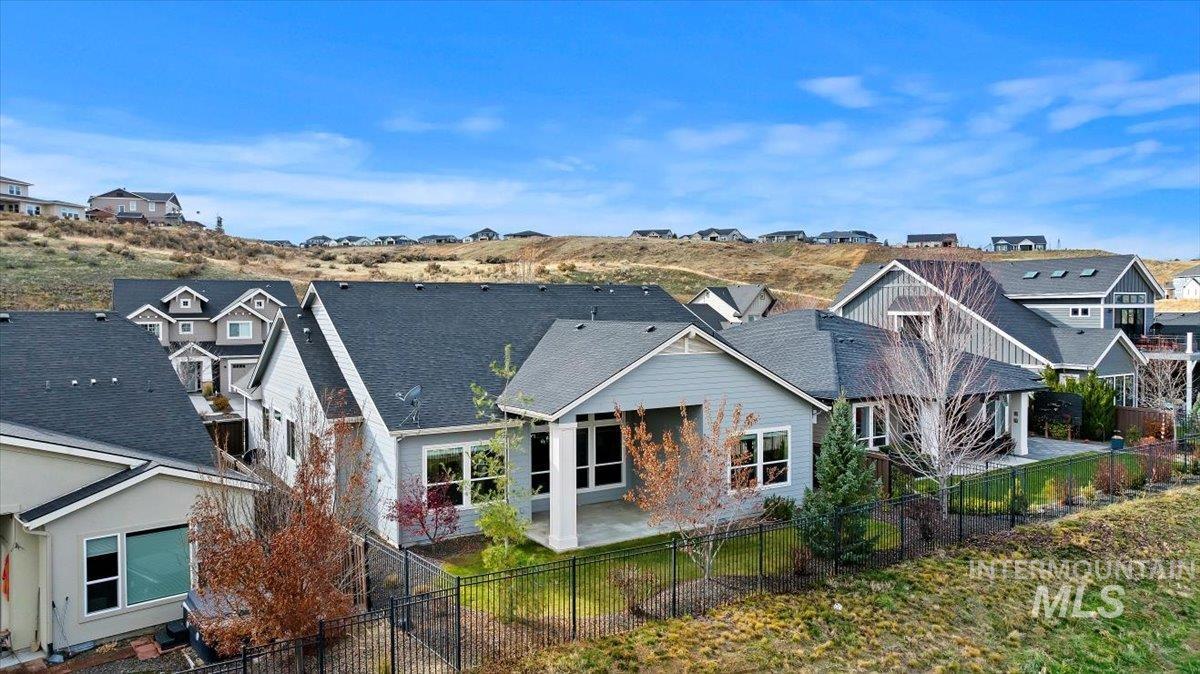 Rear view of property featuring a patio, a residential view, a fenced backyard, and roof with shingles
