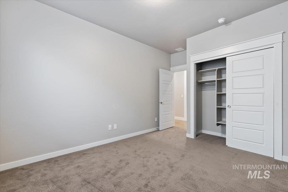 Unfurnished bedroom featuring light carpet and a closet