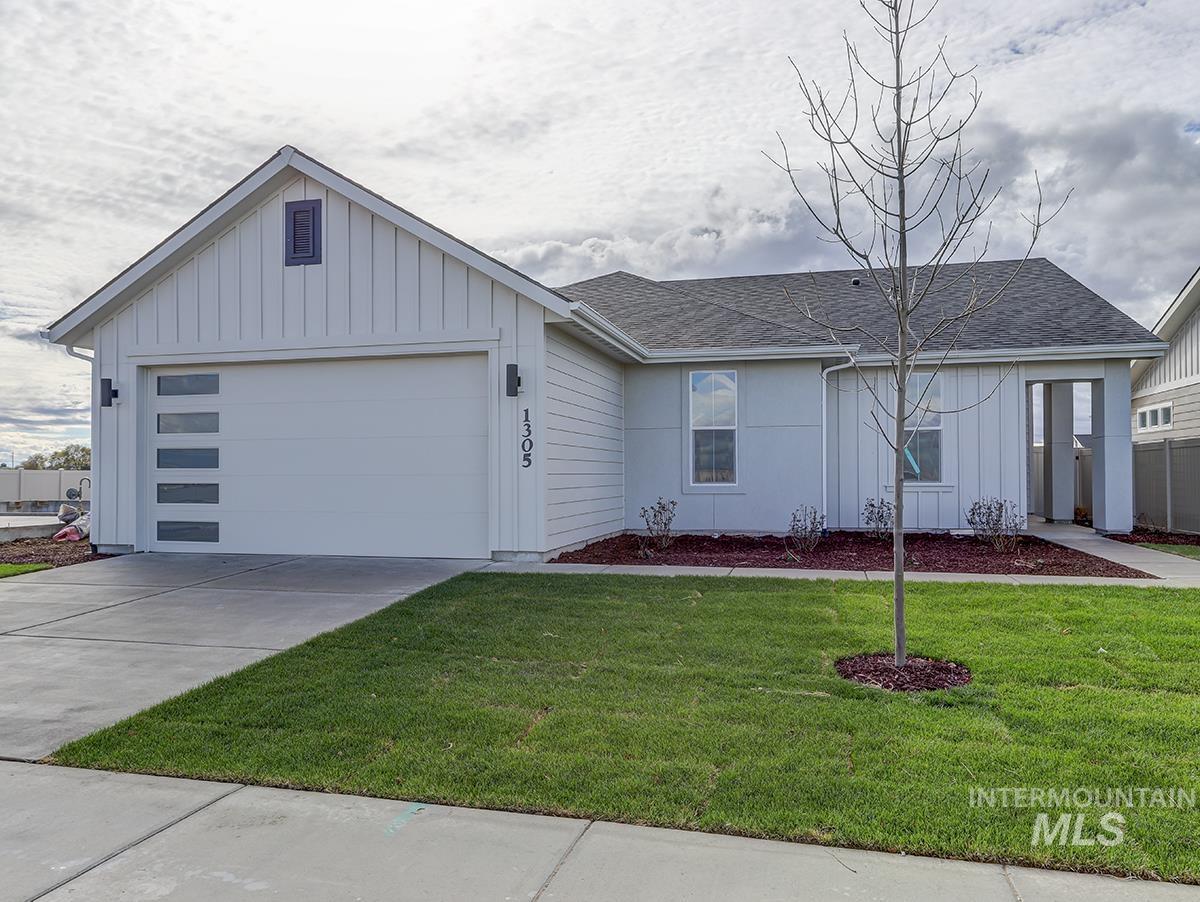 View of front facade featuring board and batten siding, a front yard, driveway, and an attached garage