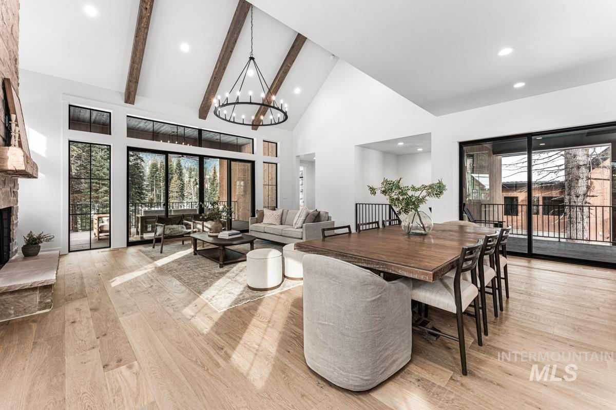 Dining area with vaulted ceiling, a fireplace, light wood-style flooring, and a chandelier