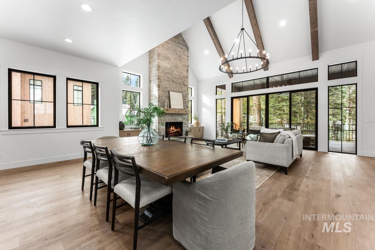 Dining area with light wood-type flooring, a fireplace, lofted ceiling, and suspended lighting