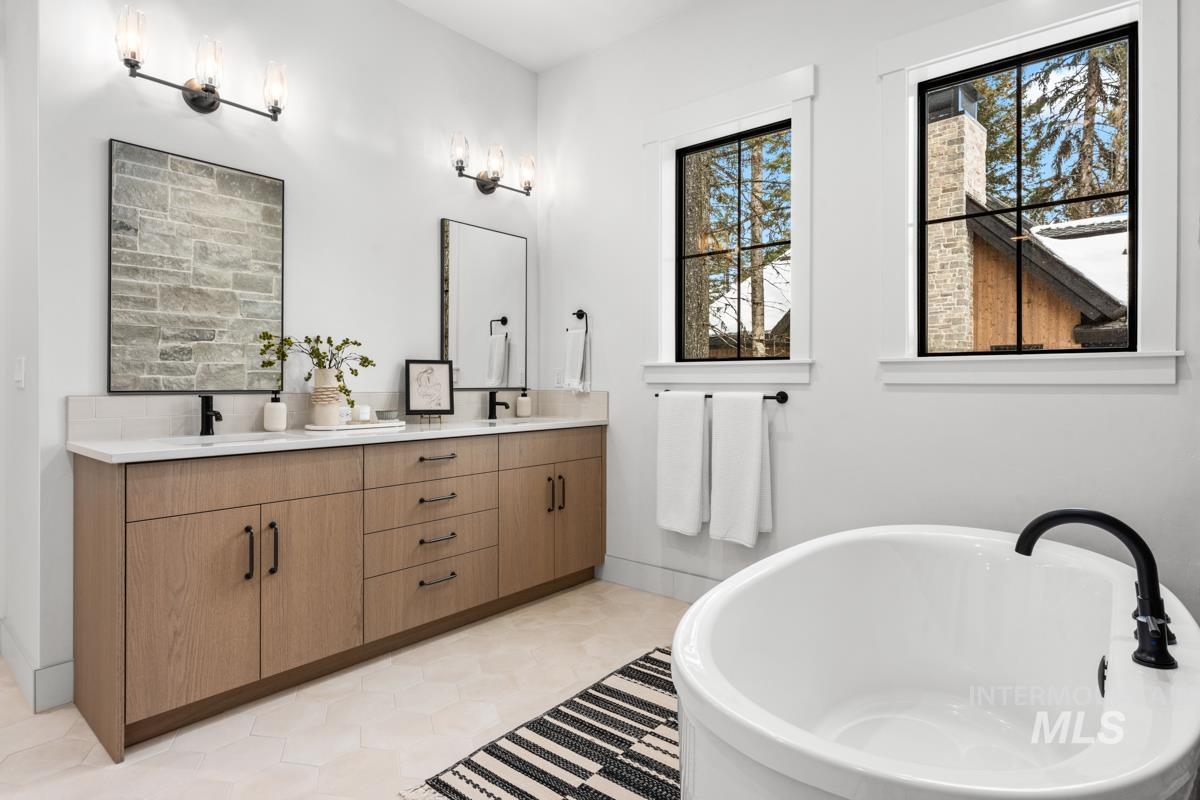 Full bathroom featuring double vanity, a soaking tub, and light tile patterned floors