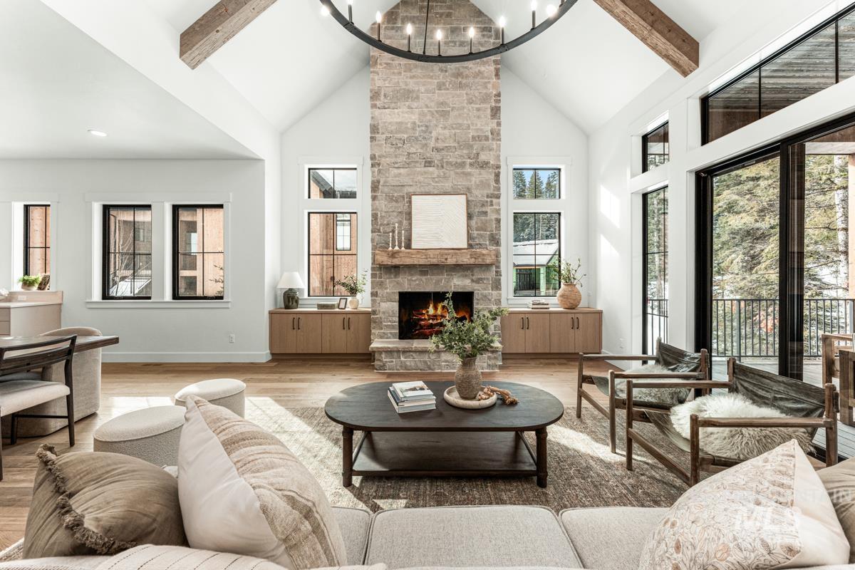 Living room with a chandelier, wood finished floors, and a stone fireplace