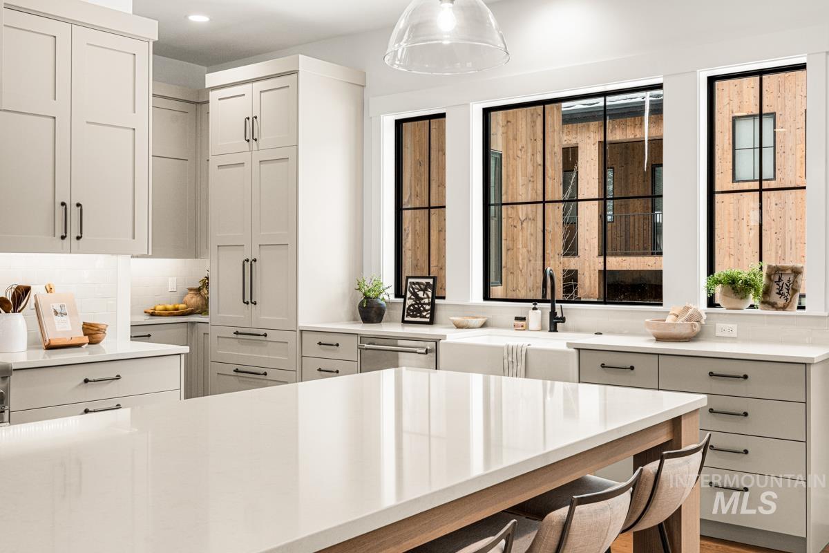 Kitchen featuring tasteful backsplash, a breakfast bar, decorative light fixtures, stainless steel dishwasher, and light stone counters