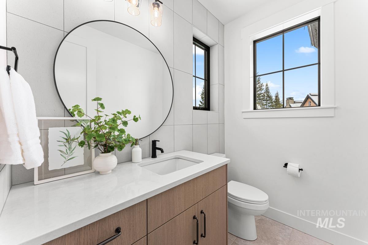 Half bathroom featuring vanity, tile walls, and light tile patterned flooring