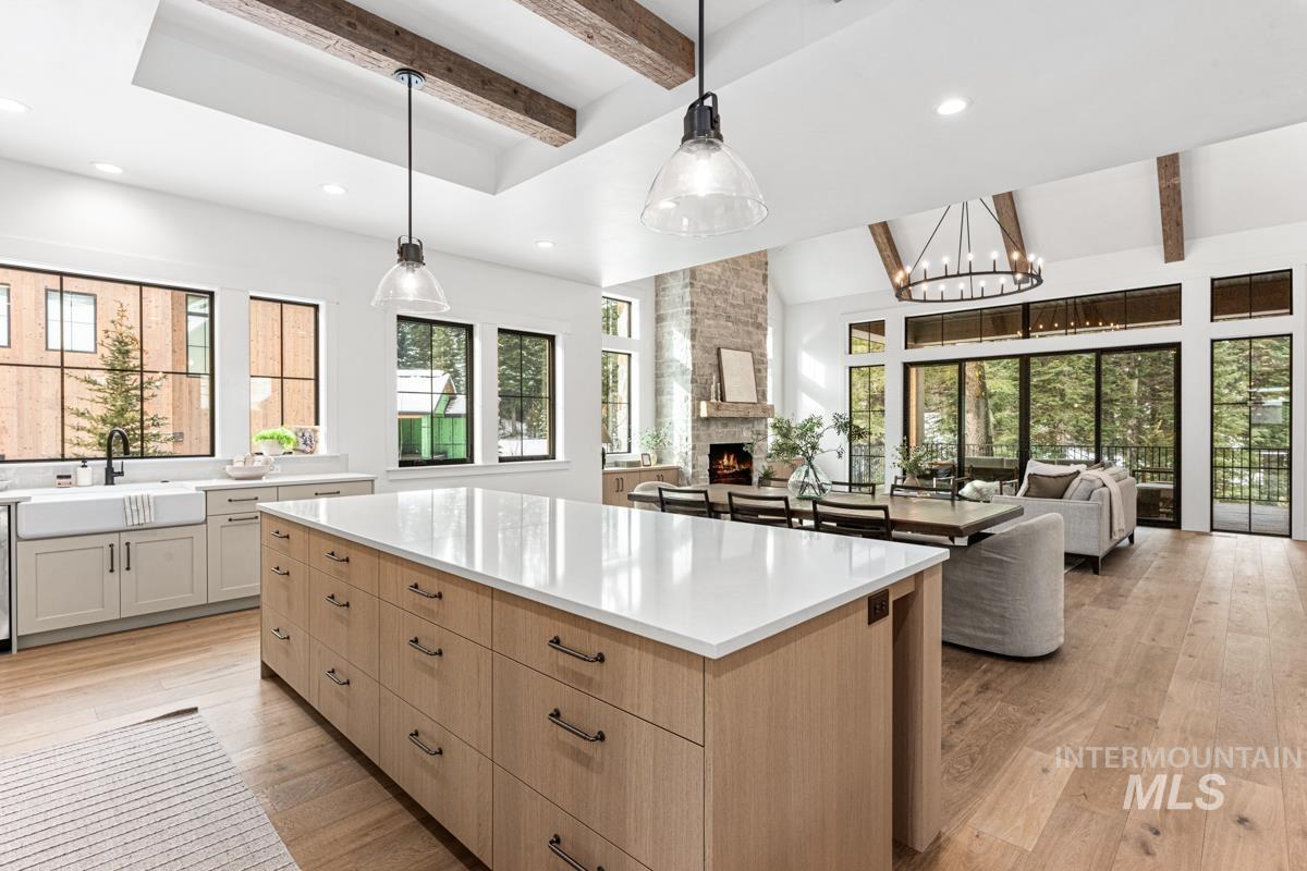 Dual tone kitchen with open floor plan, a spacious island, dual tone cabinets, light wood-style flooring, and a fireplace